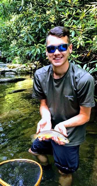 A small boy wearing glasses holding a fish