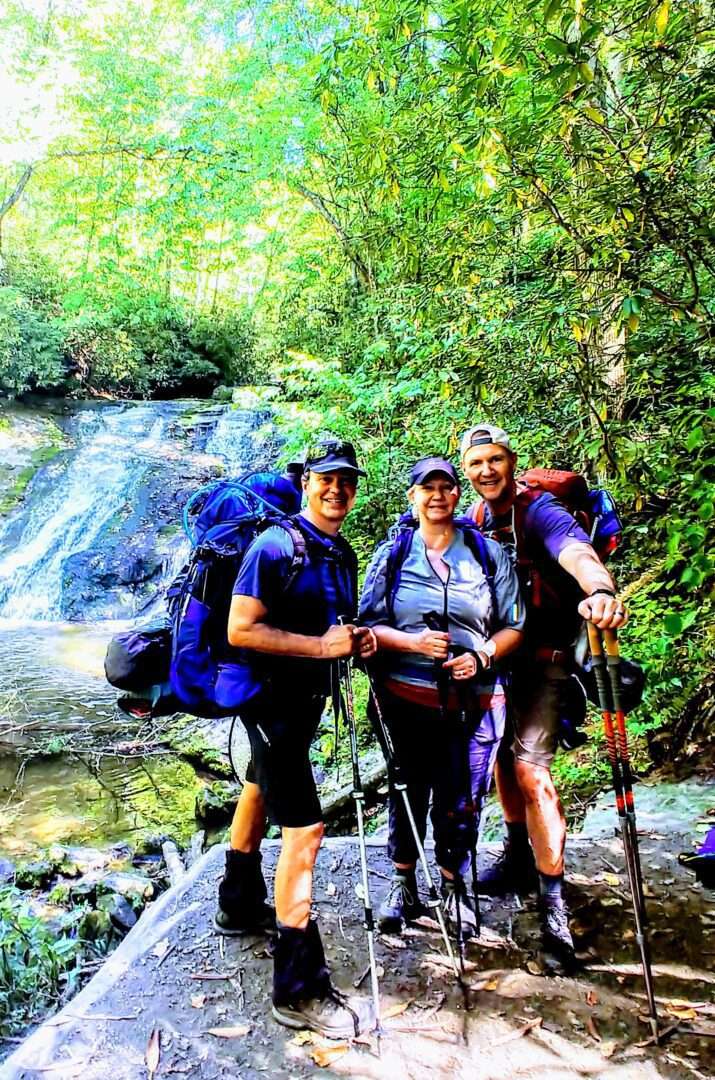 Three people backpacking at a jungle
