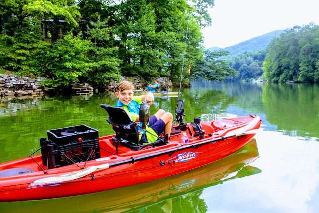 A small boy holding a fish on a red boat