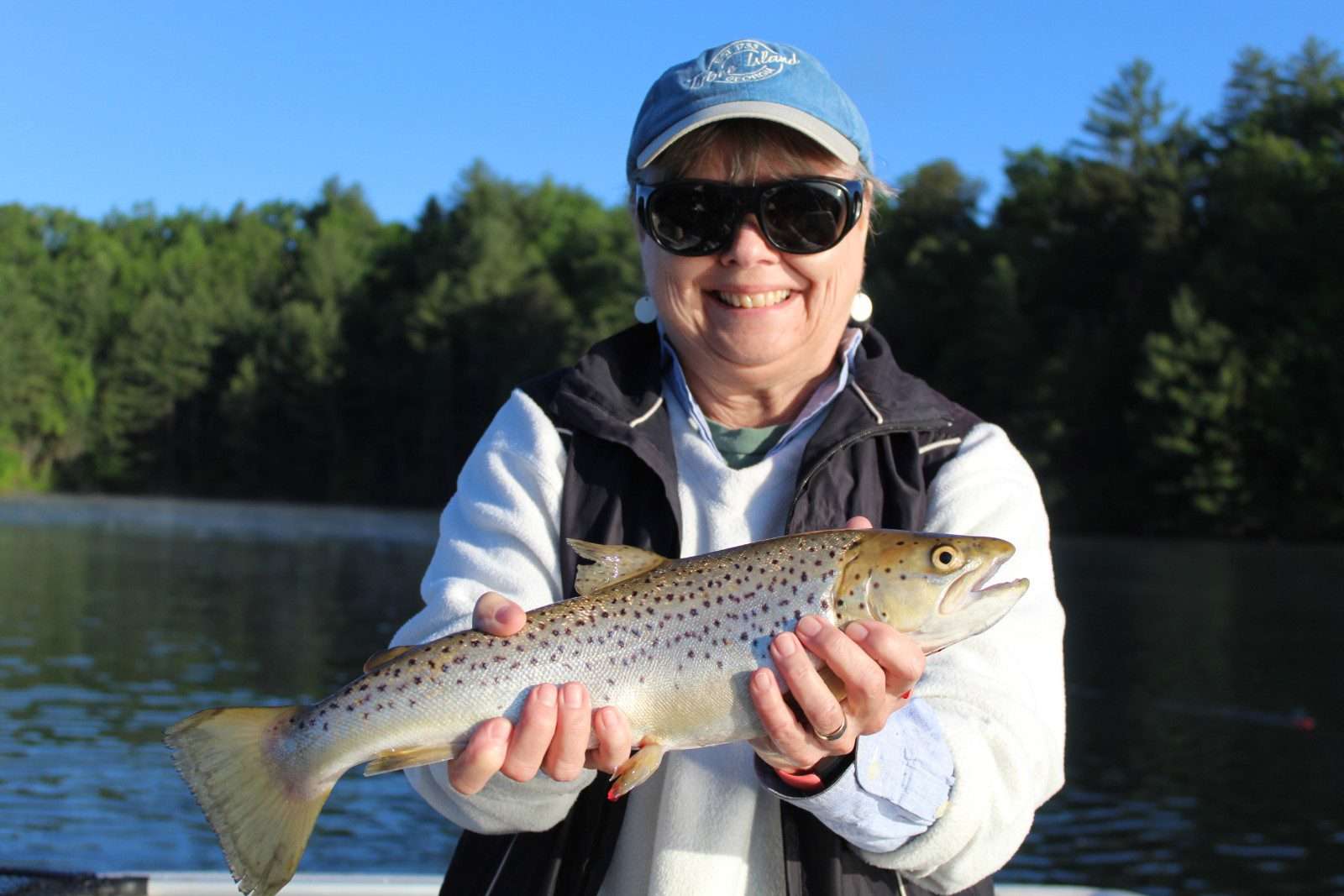A woman holding a large fish, smiling at the camera