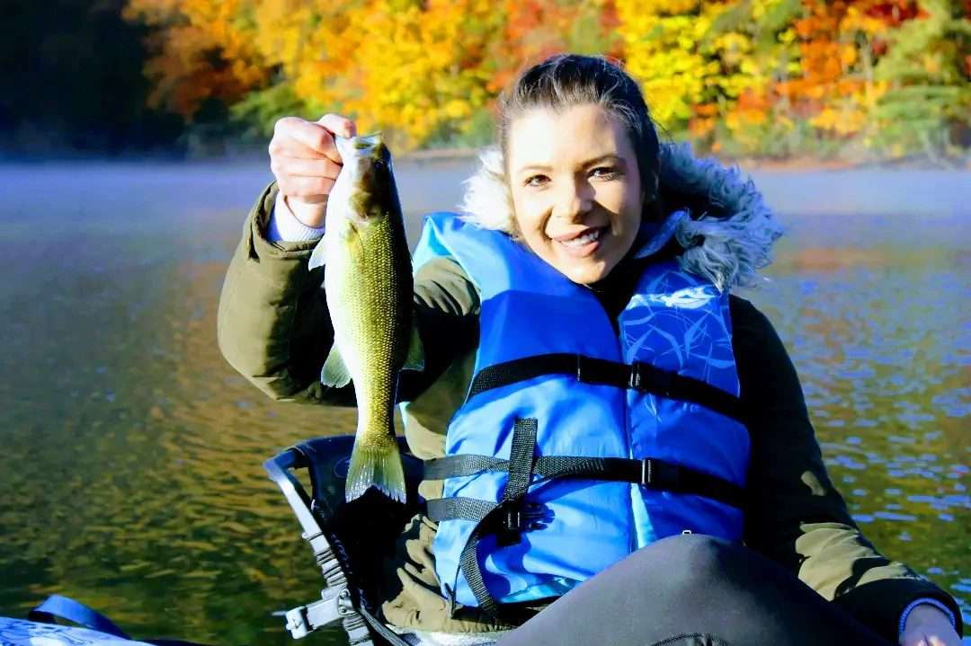 A small girl holding a fish and smiling