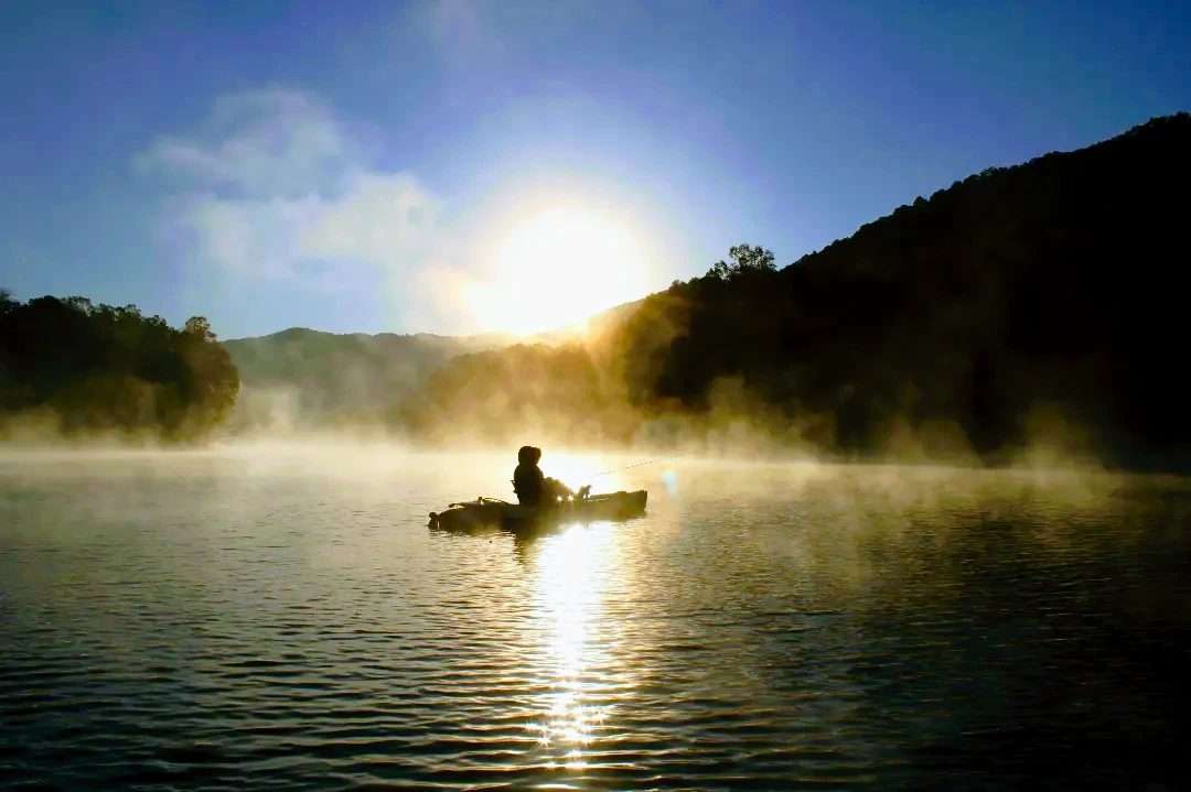 A boy sitting on a boat in an open lake
