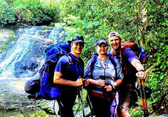 Three people backpacking at a jungle